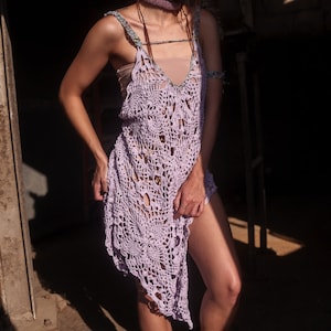 May include: A light purple crochet dress with a delicate floral pattern. The dress has a loose, flowing fit and a high neckline.
