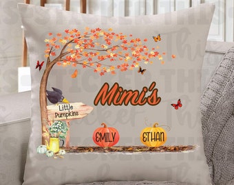 May include: A decorative throw pillow with a fall theme. The pillow features a brown tree with orange and yellow leaves, a black bird, a sign that says "Little Pumpkins", and two pumpkins with the names "Emily" and "Ethan". The pillow also has the text "Mimi's" in brown letters.