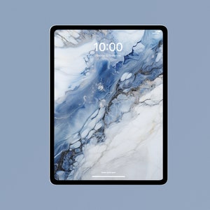 Op de afbeelding: Een zwarte tablet met een blauw en wit marmerachtig achtergrondscherm. De tijd 10:00 uur en de datum dinsdag 22 september worden weergegeven. De tablet staat tegen een lichtblauwe achtergrond.