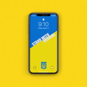 Könnte beinhalten: Ein Smartphone mit blauem und gelbem Hintergrund und dem Text "STAND WITH UKRAINE" auf dem Bildschirm. Das Telefon zeigt auch das ukrainische Wappen und die Uhrzeit 9:10 an.