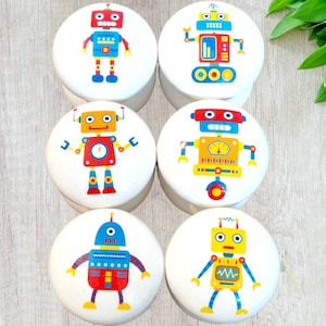 May include: Six round white ceramic containers with colorful robot designs. Each container features a different robot with various colors, including red, blue, yellow, and white.