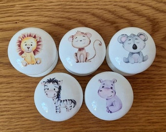Puede incluir: Cinco pomos de armario de cerámica blanca con adorables ilustraciones de animales. Los pomos presentan un león, un mono, un koala, una cebra y un hipopótamo. Cada pomo tiene forma redonda y es adecuado para una habitación infantil.