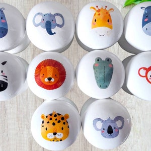 May include: Set of 10 white ceramic knobs with colourful animal illustrations. The animals include a zebra, lion, giraffe, elephant, hippopotamus, monkey, koala, crocodile, leopard, and rhinoceros.