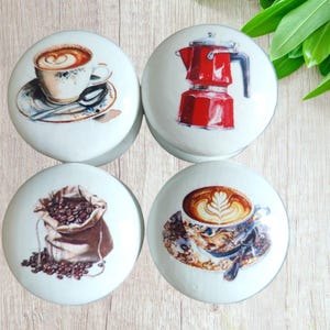 May include: Set of four ceramic knobs with coffee themed designs. The knobs feature a cup of coffee, a bag of coffee beans, a coffee pot, and a latte.