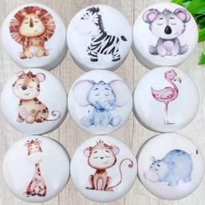 May include: Nine white ceramic knobs with different animal illustrations. The animals include a lion, zebra, koala, leopard, elephant, flamingo, giraffe, monkey, and hippopotamus. The animals are all depicted in a cartoon style with watercolor-like details.