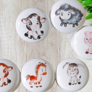Puede incluir: Seis pomos de cerámica blanca con ilustraciones de diferentes animales de granja. Los animales incluyen una vaca, un cerdo, una oveja, un caballo y un burro. Los pomos son perfectos para añadir un toque de fantasía a cualquier habitación.
