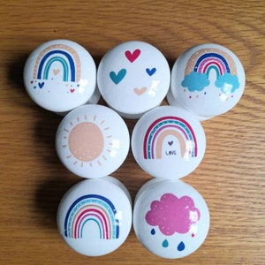 Peut inclure: Ensemble de 7 boutons ronds blancs avec des motifs arc-en-ciel, soleil, cœur et nuage colorés. Les boutons ont une finition brillante et sont parfaits pour ajouter une touche de fantaisie à n'importe quelle pièce.