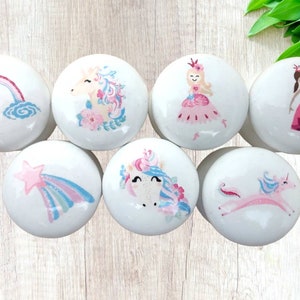 May include: Set of seven white ceramic drawer knobs with colorful unicorn, rainbow, and princess designs.