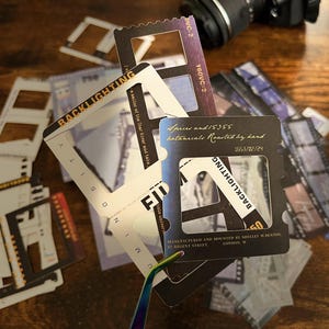 May include: A set of black and white film negative frames with the text "Backlighting" and "Spices and 15355 botanicals Roasted by hand 1653/02/24" printed on them.