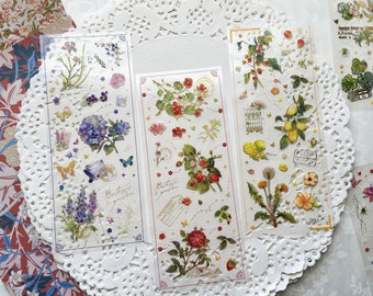 May include: Three sheets of decorative stickers featuring floral and botanical designs. The stickers are on a white background with gold accents. The stickers feature images of flowers, leaves, butterflies, and other nature-inspired elements. The text on the stickers reads "Botanic garden".