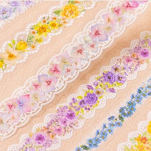 May include: Five rolls of decorative washi tape with floral patterns and lace trim. The tape features a variety of colors, including blue, purple, pink, yellow, and white.