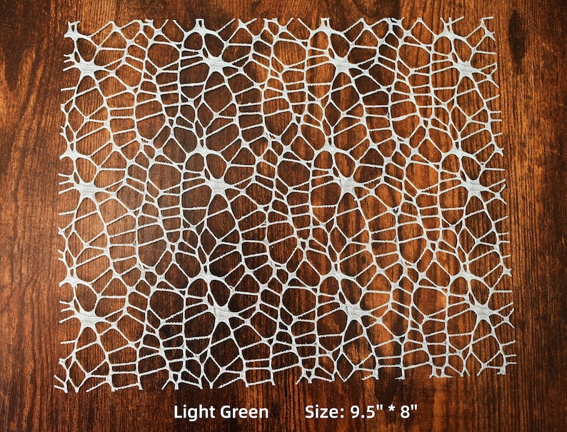 Op de afbeelding: Een lichtgroene kant tafelkleed met een geometrisch patroon. Maat: 9,5" x 8"