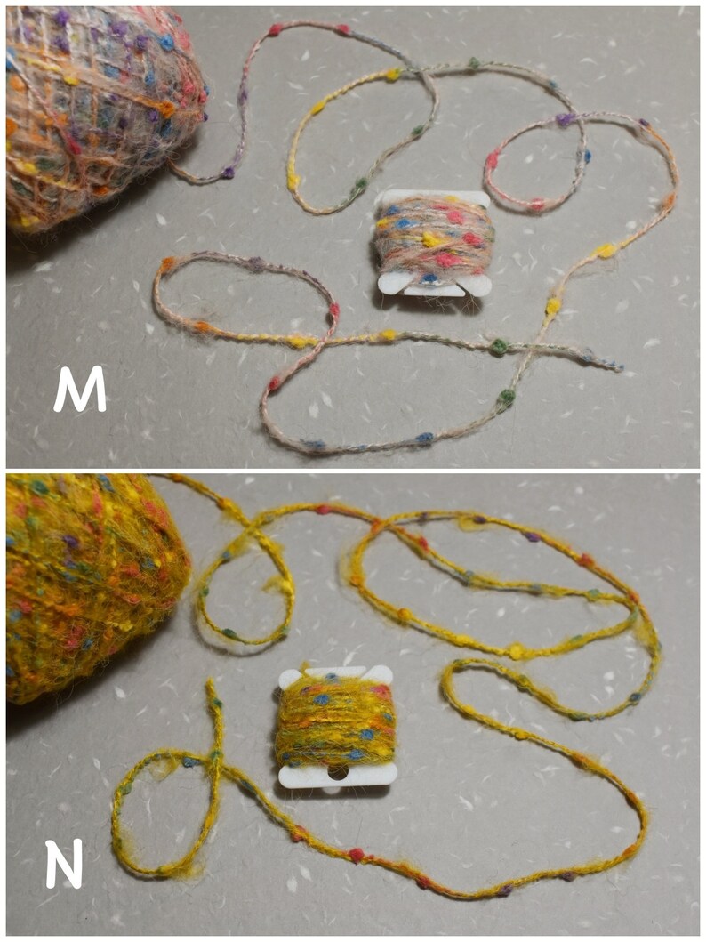 Puede incluir: Dos ovillos de hilo, uno beige y otro amarillo, con motas de colores. Cada ovillo est&aacute; enrollado alrededor de un centro de cart&oacute;n y tiene un peque&ntilde;o ovillo de hilo colorido enrollado que est&aacute; unido a &eacute;l. Los ovillos est&aacute;n etiquetados como "M" y "N".