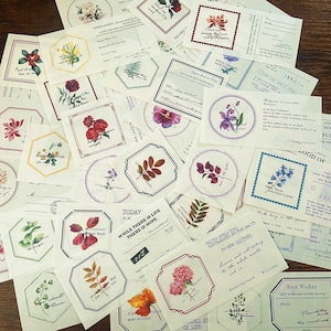 May include: Assortment of decorative paper stickers with various designs and quotes. The stickers feature floral patterns, inspirational messages, and whimsical illustrations. The stickers are printed on a cream-colored paper with a textured finish.