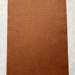 May include: A reddish-brown sheet of textured material. The surface has a bumpy, leather-like appearance. The text "Reddish-brown" is printed in a cursive font at the bottom of the image. The material is likely used for crafting or design projects.
