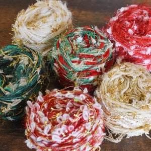 May include: Six balls of yarn in various colors, including red, green, white, and gold. The yarn is fluffy and has a sparkly texture.