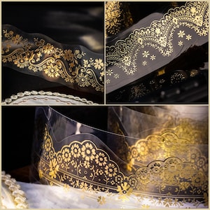 Op de afbeelding: Close-up van decoratieve goudfolietape met bloemen- en kanten patronen. De transparante tape heeft ingewikkelde gouden ontwerpen, waaronder bloemen, bladeren en delicate kanten randen. De tape is opgerold en toont de zich herhalende patronen.