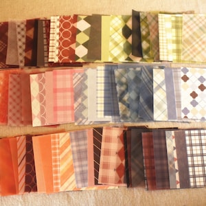 Puede incluir: Una colección de 48 cuadrados de papel con patrones en varios colores y diseños, incluyendo cuadros, vichy y patrones geométricos. Los papeles están dispuestos en tres filas, con 16 cuadrados en cada fila.