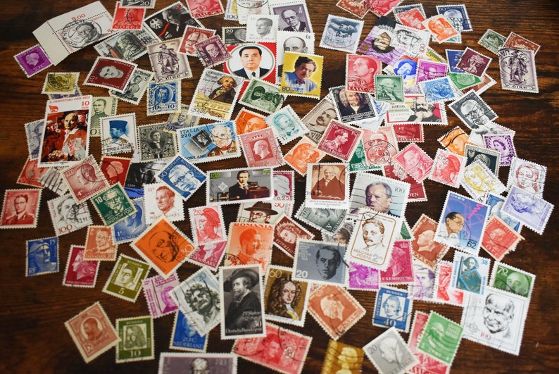 May include: A collection of vintage postage stamps featuring portraits of historical figures and landmarks. The stamps are arranged in a random pattern on a wooden surface. Some of the stamps are from Italy, Romania, and other countries.