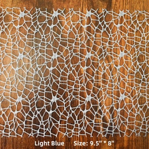 Op de afbeelding: Een lichtblauwe kant tafelkleed met een delicaat web-achtig patroon. Maat: 9,5" x 8"