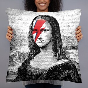 May include: Black and white illustration of the Mona Lisa with a red and blue lightning bolt painted over her eye. The image is printed on a white pillowcase.