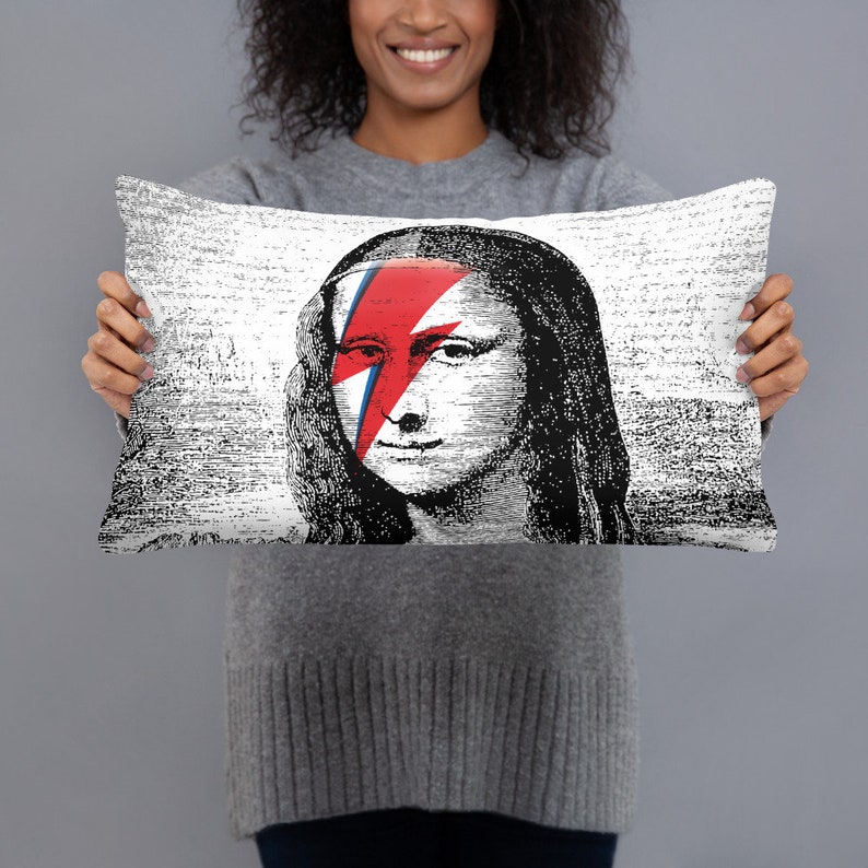 May include: A white throw pillow with a black and white image of the Mona Lisa with a red and blue lightning bolt across her face.