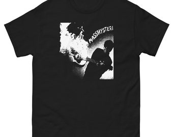 May include: Black t-shirt with a white graphic. The graphic features a silhouette of a person playing a guitar, with the word "MASSHYSTERI" above. The design has a distressed, vintage look.