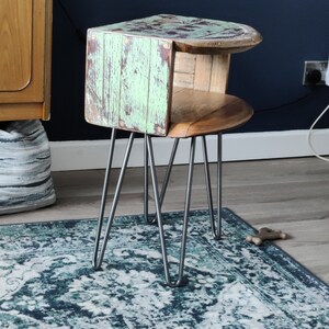 Könnte beinhalten: Einzigartiger Beistelltisch mit einer Oberfläche und Seiten aus verwittertem mintgrünem und braunem Holz. Der Tisch hat ein geschwungenes Design und wird von silbernen Haarnadelbeinen getragen. Ein stilvolles Akzentstück.