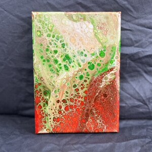 May include: Abstract painting on canvas with green, white, and red colors. The paint has been poured and swirled to create a unique pattern of cells and bubbles.