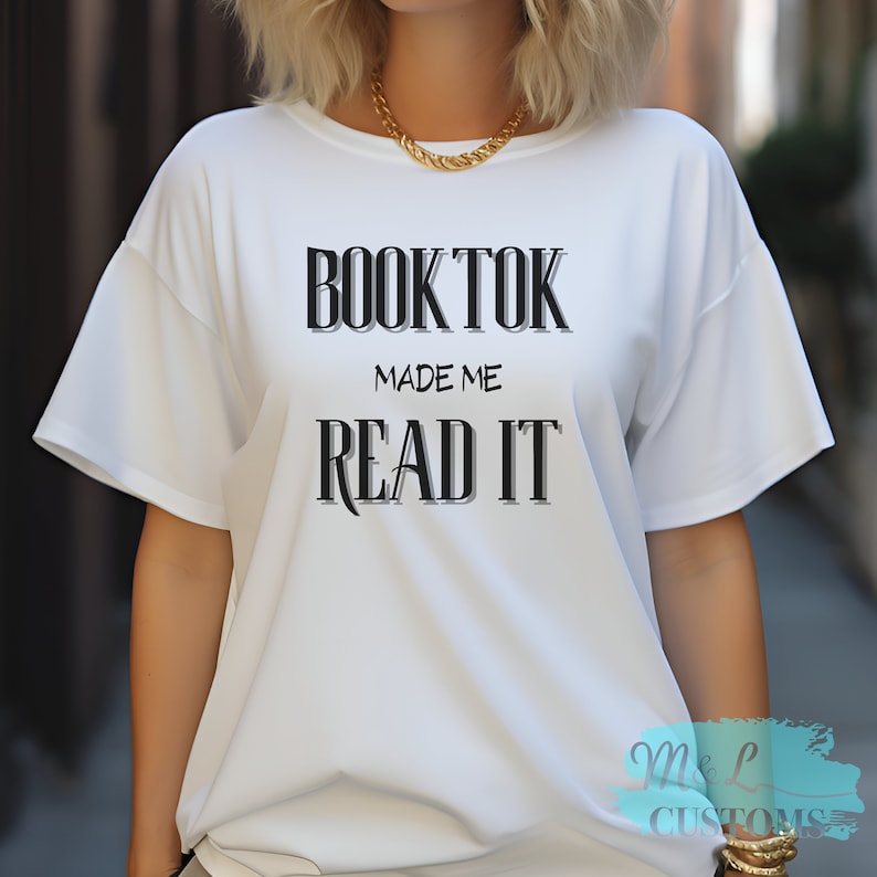 Puede incluir: Camiseta blanca con texto negro que dice "BookTok Made Me Read It"