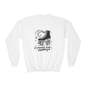 Può includere: Felpa bianca con grafica in bianco e nero di un pattino a rotelle, un cuore e stelle. Il testo "I wheely love skating" è stampato sotto. Maniche lunghe, girocollo.