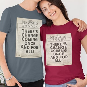 May include: Two people wearing matching t-shirts with a vintage newspaper design. The text on the shirts reads "The Newsies Banner There's Change Coming Once And For All!"