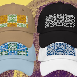 May include: Four baseball caps in tan, black, light blue, and white. Each cap features an embroidered design of three cat-like figures in a repeating pattern. The cat figures are in various colors, including yellow, green, and blue.