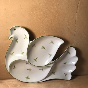 May include: A white ceramic dove-shaped serving dish with a green trim and a green leaf pattern. The dish is divided into three sections.