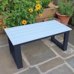 May include: A light blue wooden bench with a dark grey frame. The bench is made of wood planks and has a simple, modern design.