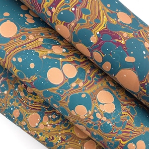 May include: A sheet of paper featuring a marbled pattern with a teal background, accented by swirling lines of yellow and deep red, and interspersed with numerous solid, circular peach-coloured spots of varying sizes across the entire surface.