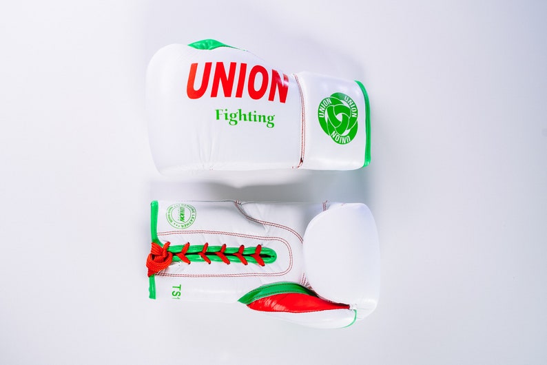 May include: A pair of white boxing gloves with green and red trim. The gloves have the text "UNION Fighting" on one glove and a green logo on the other.