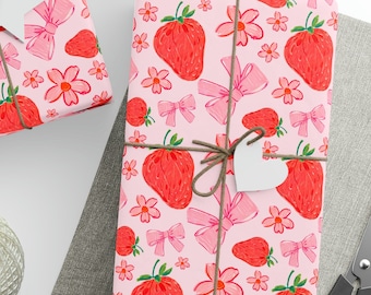 May include: Pink wrapping paper with a pattern of strawberries, flowers, and bows. The paper is wrapped around a gift box with a white star-shaped tag.