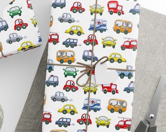 Puede incluir: Papel de regalo blanco con un patrón repetido de coches de dibujos animados de colores. Los coches son rojos, azules, amarillos, verdes y naranjas. Algunos de los coches tienen un símbolo de ambulancia blanco en el lateral.