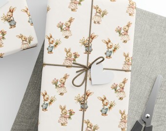 May include: White gift wrap with a repeating pattern of brown rabbits holding flowers. The rabbits are wearing blue and pink clothing. The wrapping paper is tied with brown twine and has a white heart-shaped tag.