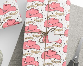 May include: Pink and gold cowboy hat wrapping paper with the words "Howdy Honey" repeated on a white background.