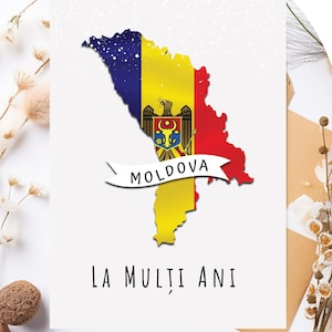 Könnte beinhalten: Eine weiße Karte mit einer blauen, gelben und roten Karte von Moldawien mit dem Staatswappen des Landes. Die Karte ist schwarz umrandet und hat ein weißes Band mit dem Wort "MOLDOVA" in Schwarz. Die Karte hat auch den Text "LA MULȚI ANI" in Schwarz.