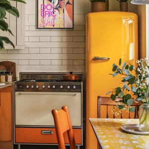 May include: A yellow vintage refrigerator with a wooden chair and a table in front of it. A framed print with the words "Do Epic Shit" hangs on the wall above the stove.
