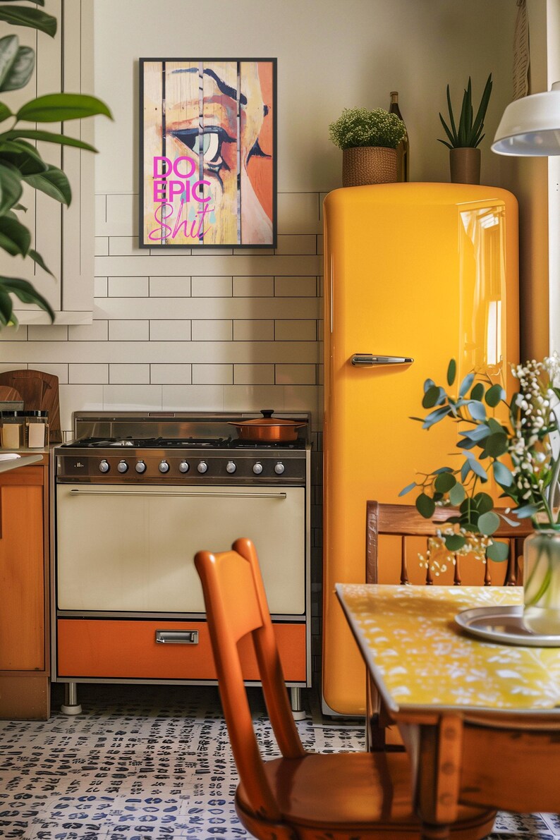 May include: A yellow vintage refrigerator with a wooden chair and a table in front of it. A framed print with the words "Do Epic Shit" hangs on the wall above the stove.