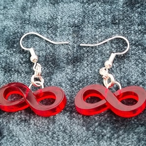May include: A pair of red infinity symbol earrings with silver hooks. The earrings are made of acrylic and are a bright, vibrant red.