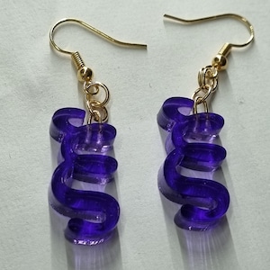 Puede incluir: Un par de pendientes de acrílico morado en forma de la letra 'S'. Los pendientes están en ganchos dorados.