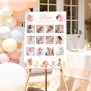 May include: A white rectangular milestone board featuring the text Rosie MY FAIRY FIRST YEAR SEPT 13TH, 2024 11:30 AM. The board displays twelve square photographs of a baby, each labeled with a month, decorated with watercolor fairy illustrations.