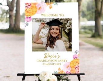 Könnte beinhalten: Ein Willkommensschild für eine Abschlussfeier auf einer schwarzen Staffelei. Das Schild zeigt ein Foto einer Absolventin mit Hut und Robe, mit dem Text "Welcome to Rosie's Graduation Party Class of 20XX". Florale Akzente in Rosa, Gelb und Orange schmücken das Schild.
