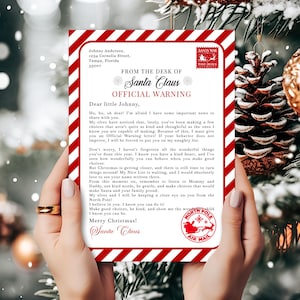 Może przedstawiać: Prostokątny list od Świętego Mikołaja z czerwono-białą ukośnie prążkowaną ramką. Tekst brzmi From the Desk of Santa Claus Official Warning, zaadresowany do Johnny'ego, ze znaczkiem Santa Mail i okrągłą pieczęcią North Pole Air Mail.