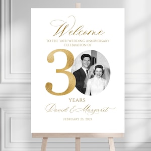 May include: A white sign with gold lettering announcing a 30th wedding anniversary celebration for David & Margaret on February 25, 2025. A black and white photograph of the couple is featured on the sign.